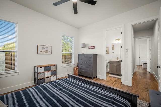 bedroom featuring baseboards, ensuite bath, wood finished floors, and ceiling fan