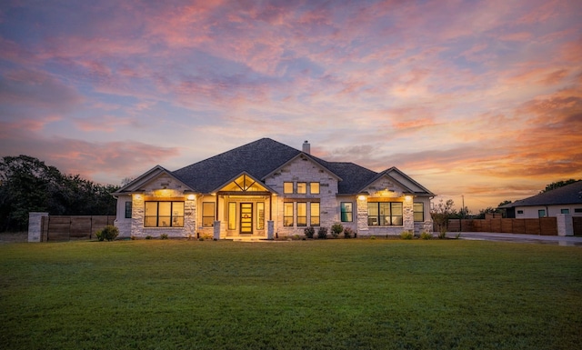 french provincial home with fence, a chimney, a front lawn, and stone siding