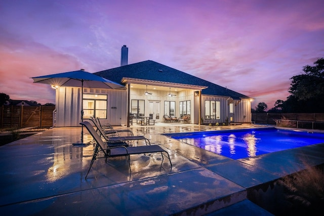 pool at dusk featuring a patio and ceiling fan