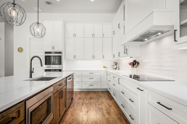 kitchen featuring pendant lighting, custom exhaust hood, white cabinetry, a sink, and appliances with stainless steel finishes