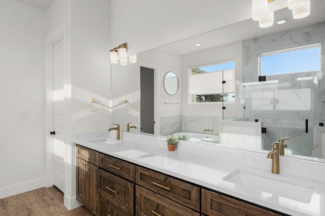 bathroom featuring a sink, double vanity, a stall shower, and wood finished floors