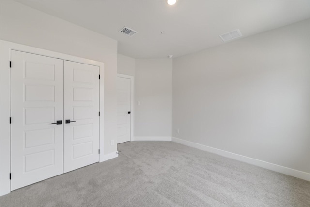 unfurnished bedroom featuring light colored carpet and a closet