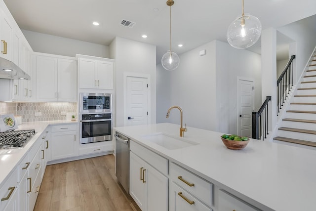 kitchen featuring decorative backsplash, stainless steel appliances, sink, pendant lighting, and white cabinetry