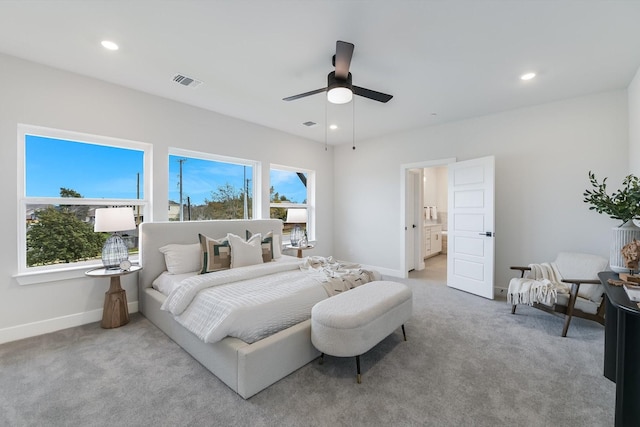 bedroom featuring ceiling fan, light colored carpet, connected bathroom, and multiple windows