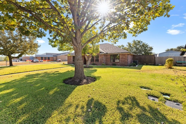 view of front of house featuring brick siding, a front lawn, and fence