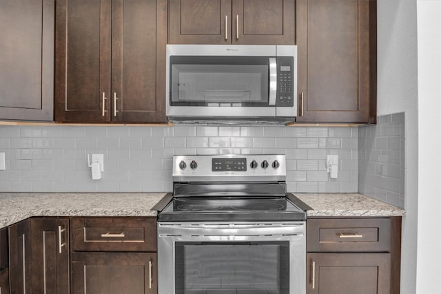 kitchen featuring appliances with stainless steel finishes, decorative backsplash, light stone countertops, and dark brown cabinets