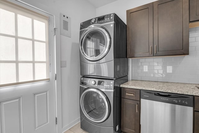 laundry room with stacked washer / drying machine and light tile patterned floors