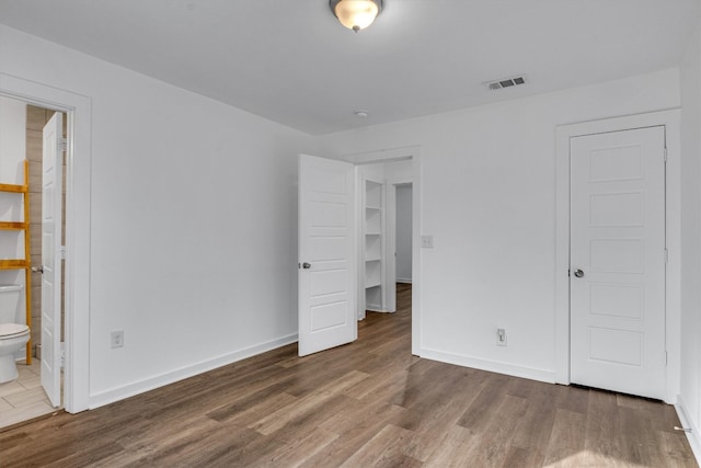 unfurnished bedroom with connected bathroom and dark hardwood / wood-style floors