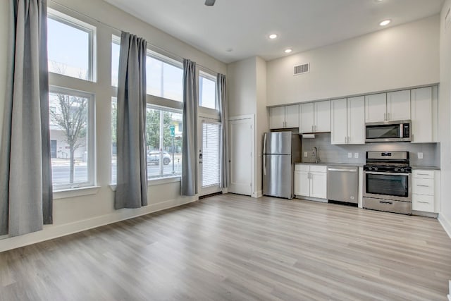 kitchen featuring light hardwood / wood-style floors, appliances with stainless steel finishes, a healthy amount of sunlight, and white cabinets