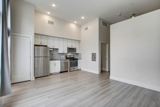 kitchen featuring sink, white cabinets, stainless steel appliances, and a towering ceiling