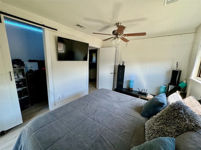 bedroom featuring ceiling fan, hardwood / wood-style flooring, and a textured ceiling