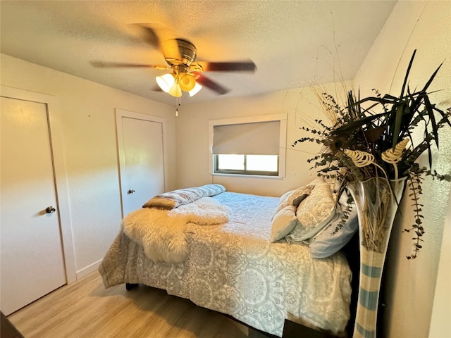 bedroom featuring ceiling fan, a textured ceiling, and light wood-type flooring