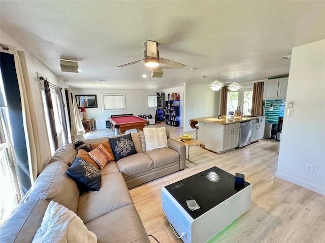 living room featuring light hardwood / wood-style flooring, pool table, a textured ceiling, and ceiling fan