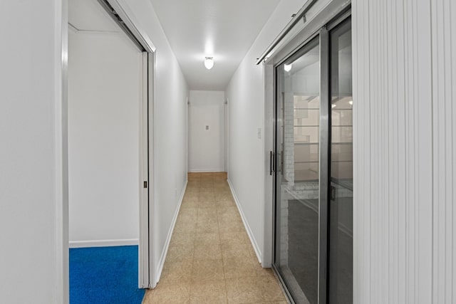 hall featuring a barn door and light tile patterned floors