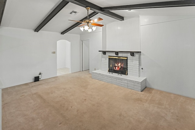 unfurnished living room featuring light carpet, lofted ceiling with beams, a brick fireplace, and ceiling fan