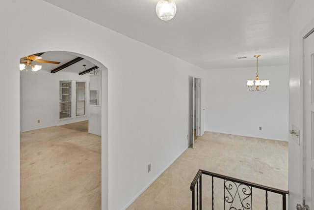 corridor with beamed ceiling, light carpet, and an inviting chandelier