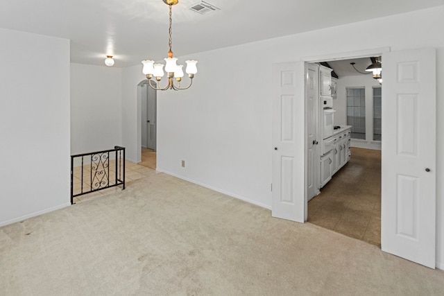 carpeted spare room with a chandelier