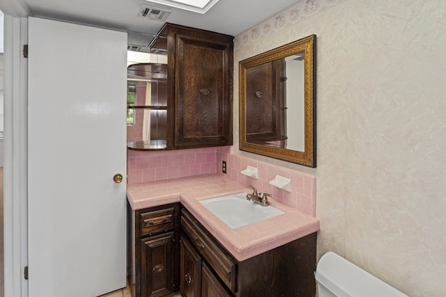 bathroom with backsplash, vanity, and toilet