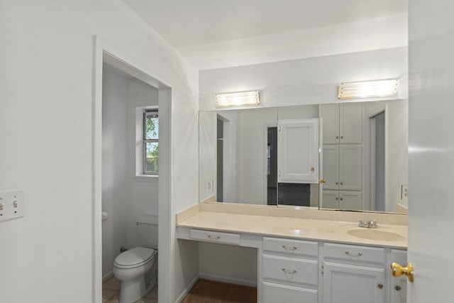 bathroom with toilet, vanity, and tile patterned floors