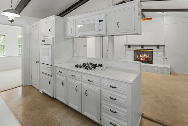 kitchen featuring lofted ceiling with beams, decorative light fixtures, white cabinets, a fireplace, and white appliances