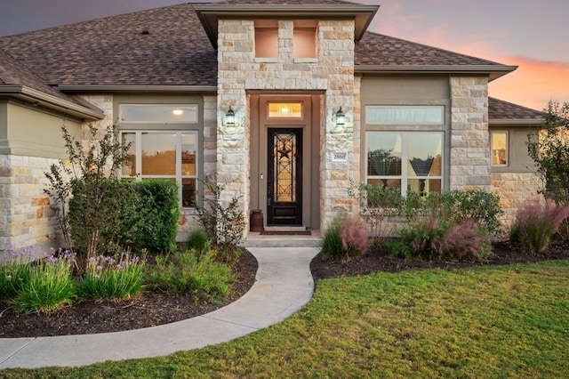 exterior entry at dusk featuring a lawn