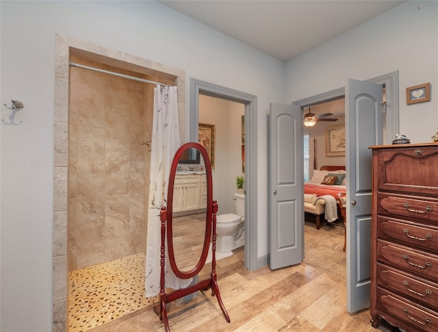 bathroom featuring toilet, hardwood / wood-style flooring, a shower with shower curtain, and ceiling fan