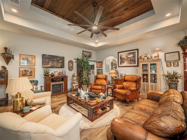 living room featuring wood ceiling, light hardwood / wood-style flooring, ceiling fan, and a raised ceiling