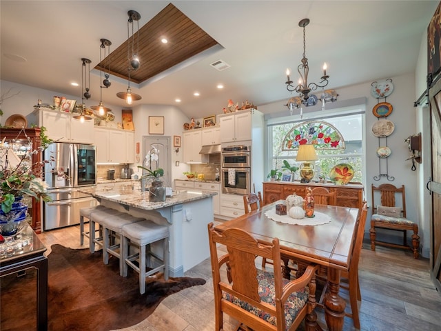 kitchen featuring appliances with stainless steel finishes, a kitchen island with sink, hanging light fixtures, and tasteful backsplash