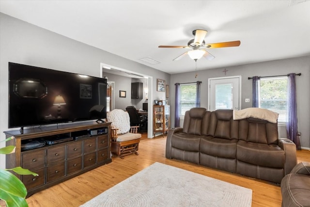 living room featuring ceiling fan, light wood-type flooring, and a wealth of natural light