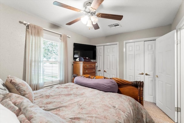 bedroom featuring carpet, ceiling fan, and multiple closets