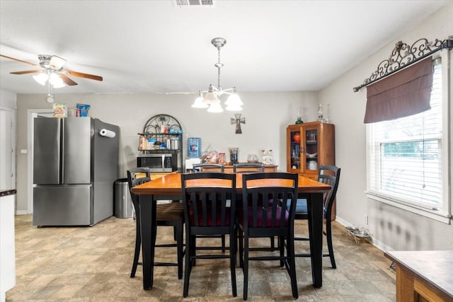 dining area featuring ceiling fan with notable chandelier