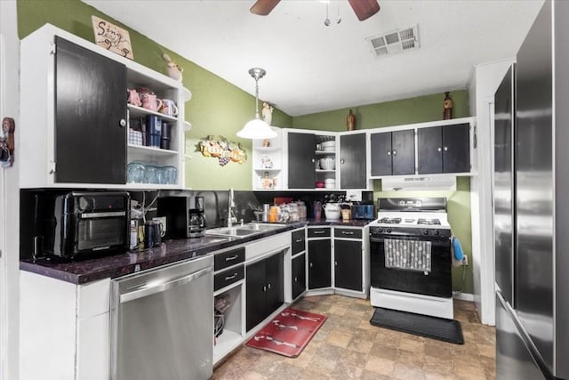 106 Hudgins St, Smithville, TX 78957 - kitchen featuring appliances with stainless steel finishes, open shelves, dark countertops, a ceiling fan, and under cabinet range hood