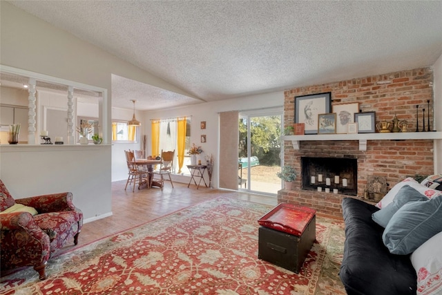 living room with hardwood / wood-style flooring, a textured ceiling, and a brick fireplace