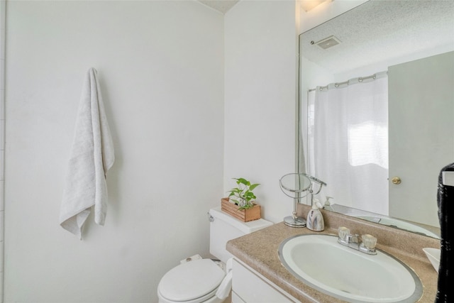 bathroom featuring toilet, a textured ceiling, curtained shower, and vanity