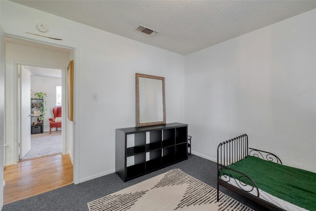 bedroom with a textured ceiling and hardwood / wood-style flooring