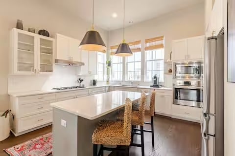 kitchen with a breakfast bar area, a center island, stainless steel appliances, light countertops, and white cabinetry