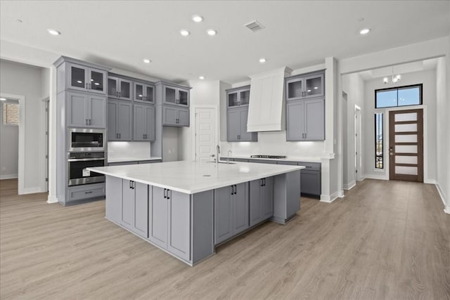 kitchen with sink, gray cabinets, appliances with stainless steel finishes, a large island, and custom range hood