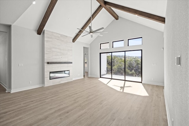 unfurnished living room with hardwood / wood-style flooring, beam ceiling, a fireplace, and high vaulted ceiling