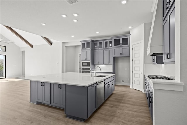 kitchen with sink, lofted ceiling with beams, a spacious island, gray cabinets, and appliances with stainless steel finishes