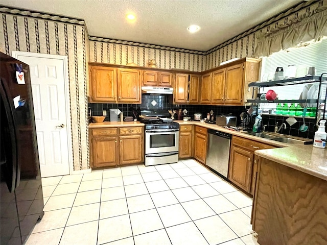 kitchen featuring appliances with stainless steel finishes, a textured ceiling, sink, and backsplash