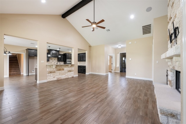 unfurnished living room with high vaulted ceiling, a stone fireplace, ceiling fan, dark hardwood / wood-style floors, and beamed ceiling