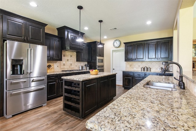 kitchen with a kitchen island, sink, light stone countertops, and stainless steel appliances