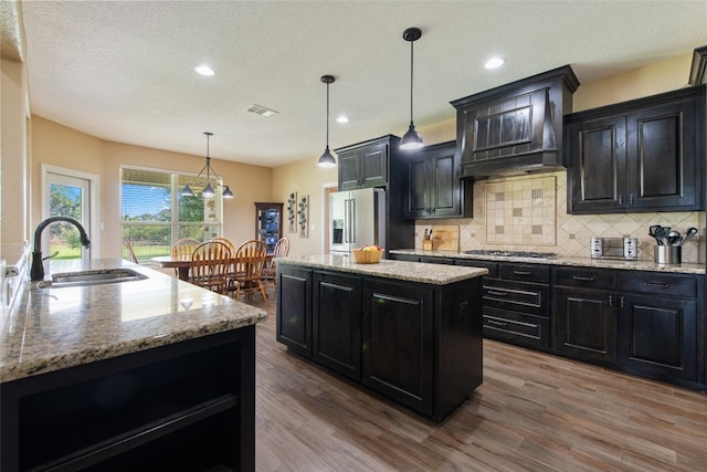 kitchen with pendant lighting, sink, a kitchen island with sink, and appliances with stainless steel finishes