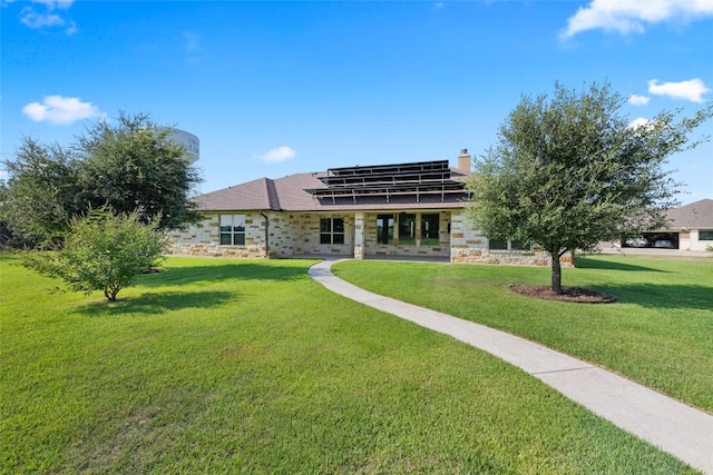 rear view of property featuring a yard and solar panels