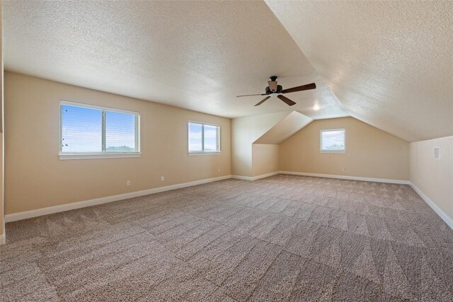 bonus room with carpet flooring, a textured ceiling, vaulted ceiling, and ceiling fan