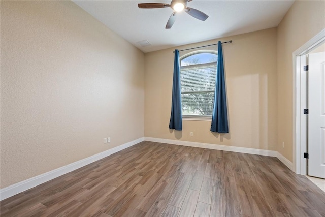 unfurnished room with a ceiling fan, baseboards, and wood finished floors