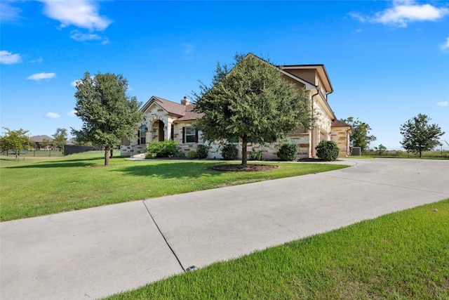 view of front facade with a front yard, stone siding, and driveway