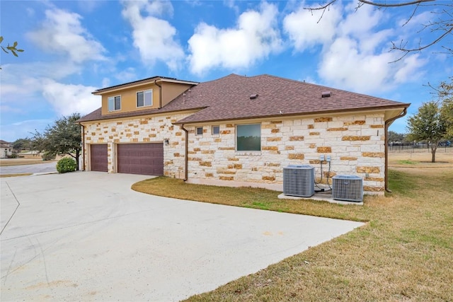 view of front of home with a garage, driveway, a front lawn, and cooling unit