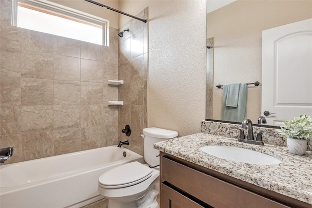 bathroom with a textured wall, vanity, bathtub / shower combination, and toilet