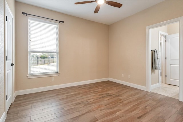 spare room with ceiling fan, light wood-type flooring, and baseboards